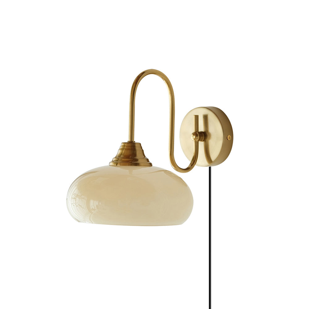 Nova plug-in wall lamp with a curved metal arm, pale glass shade and visible cord